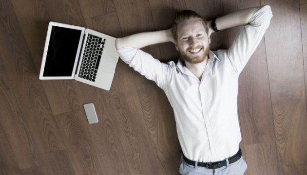 Man laying on the floor beside the laptop